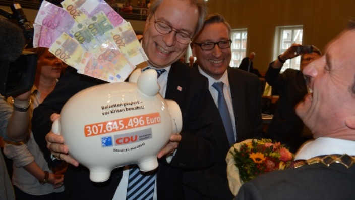 Rüdiger Gutt (l.) und Andreas Hartnigk (M.) übergeben OB Geisel das Sparschwein